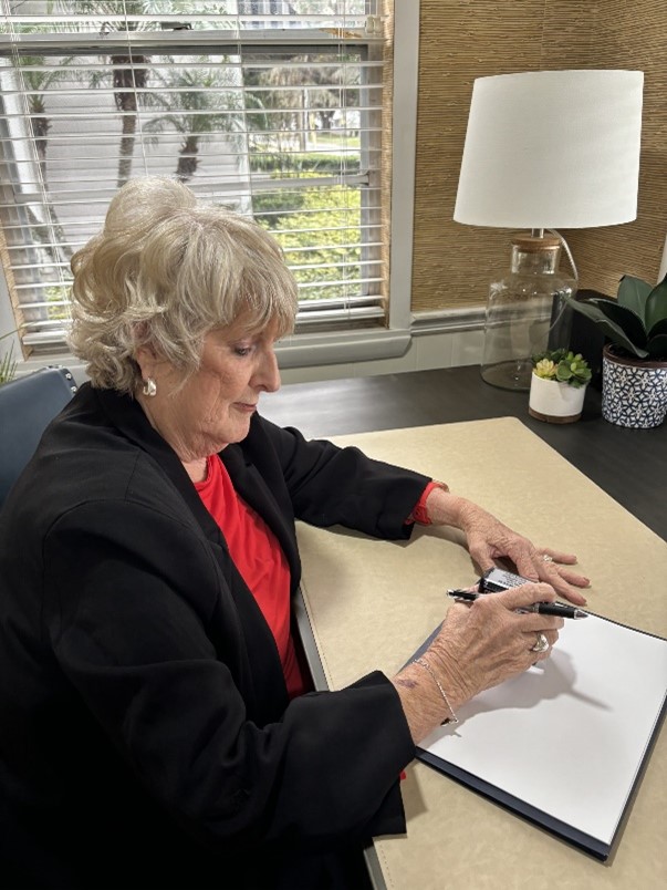 A woman sitting at a desk writing on paper.