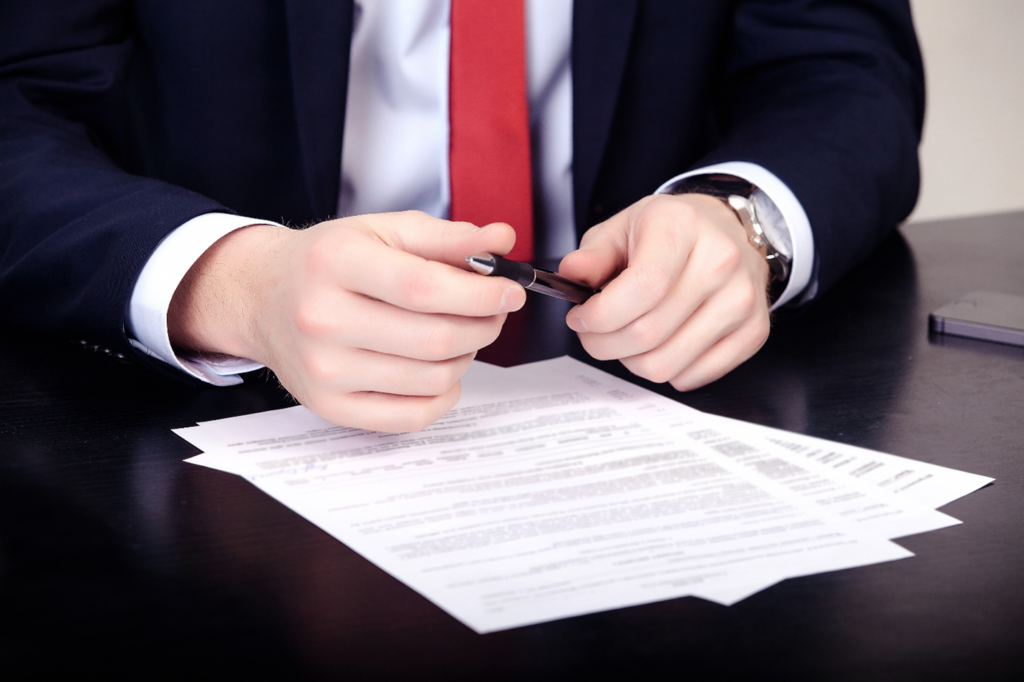 A man in a suit and tie cutting paper with scissors.