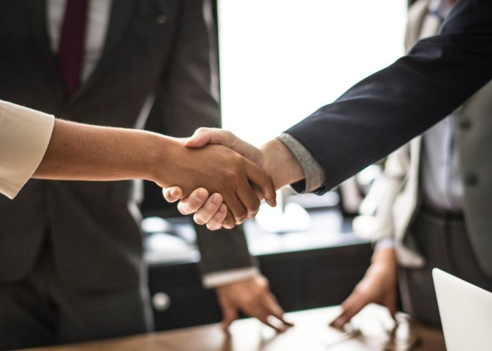 pexels-photo-1179804 Two people shaking hands over a table.