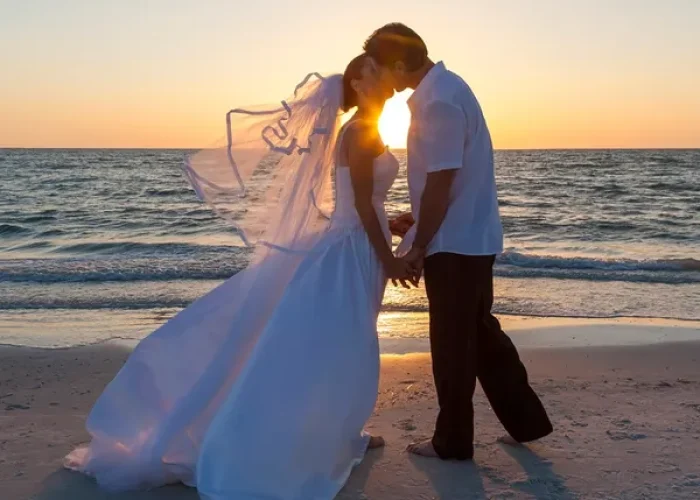 rs=w_600,h_600,cg_true (1) A bride and groom kissing on the beach at sunset.